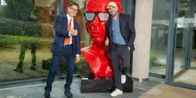 Checco Zalone e Pier Silvio Berlusconi, a sorpresa, si danno il cinque a Cologno Monzese: a &ldquo;benedirli&rdquo; l&rsquo;enorme statua rossa con la faccia dell&rsquo;attore