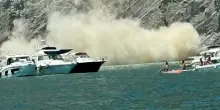 Terrore in spiaggia per la frana improvvisa: piovono pietre e rocce sui bagnanti, sfiorate anche le barche. I video dei turisti