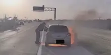 Auto in fiamme sull'autostrada, poliziotto salva un automobilista in extremis: le immagini della bodycam