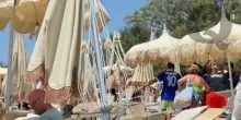 Tromba d'aria sulla spiaggia, sdraio e ombrelloni volano sui bagnanti: feriti