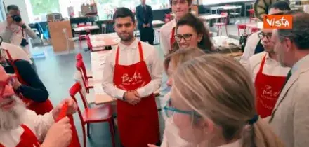 Meloni indossa il grembiule di PizzAut, durante la visita al ristorante di Monza per il Primo Maggio