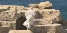 Il Papa a Lampedusa: si arrampica sugli scogli, gli vola via la papalina
