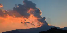 L'eruzione dell'Etna al tramonto, il fumo si tinge di un suggestivo color arancio