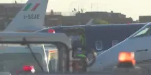 Di Battista portato fuori dall'aeroambulanza dai sanitari con la testa visibilmente fasciata