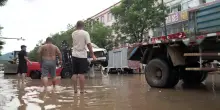 Gente in strada cammina nel fango: Pechino devastata dalle inondazioni